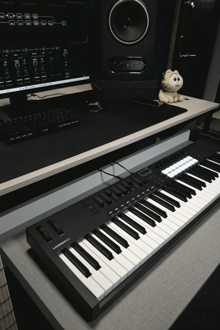 Keyboard controller on the desk shelf with the session screen and a nearfield monitor behind it.