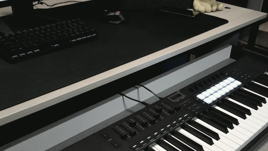 A weighted keyboard controller on the desk in front of the session screen and a nearfield monitor.