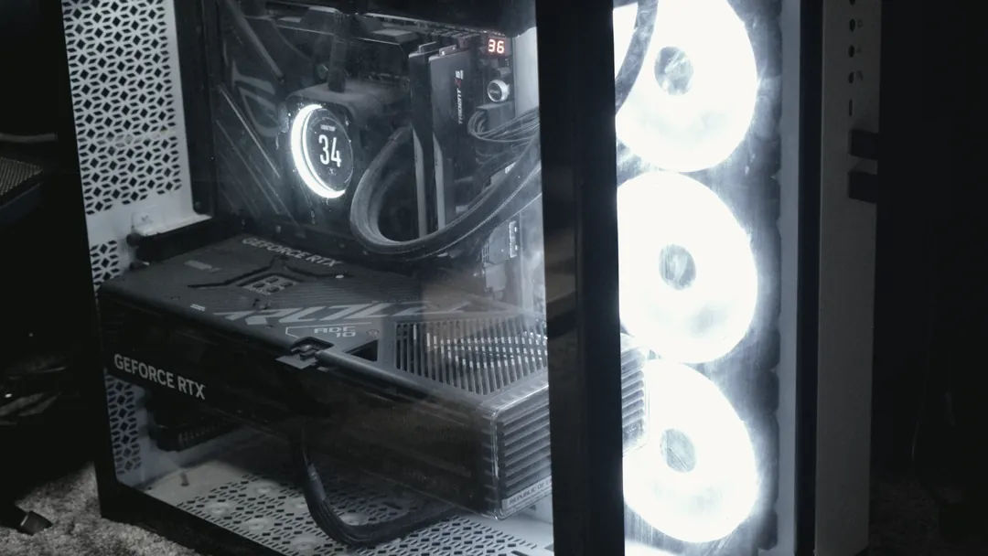 The studio workstation under the desk, its cooling fans lit, seen through a glass side panel.