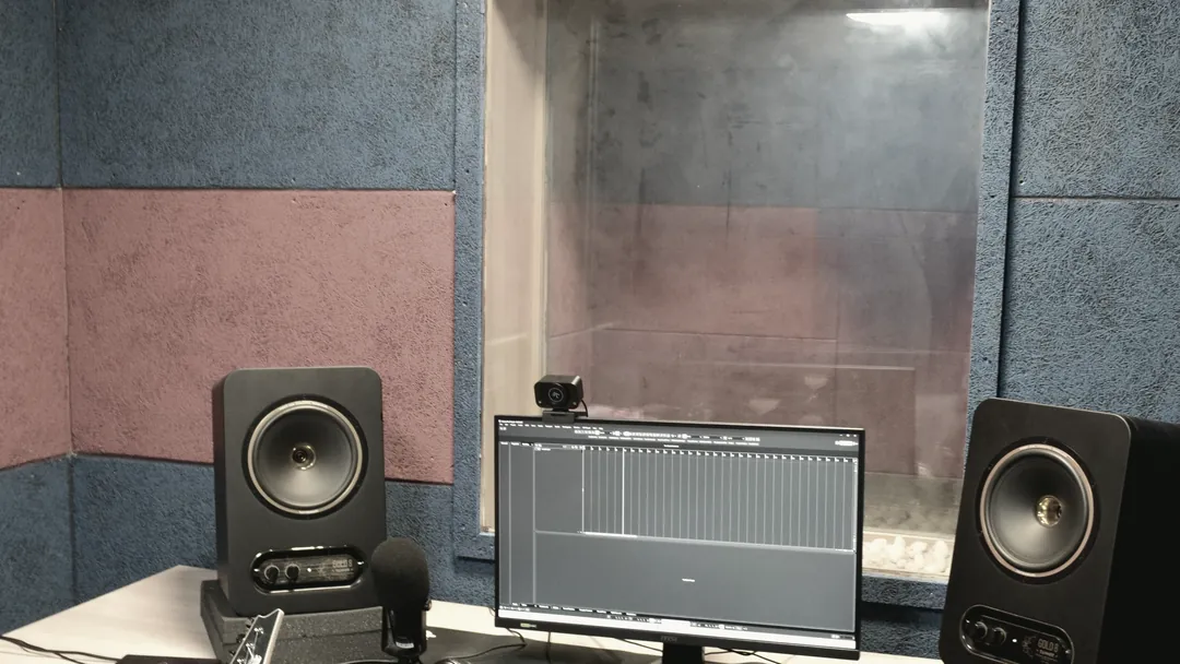 The empty live room at the end of a session, desk and monitors lit, chair pushed back.