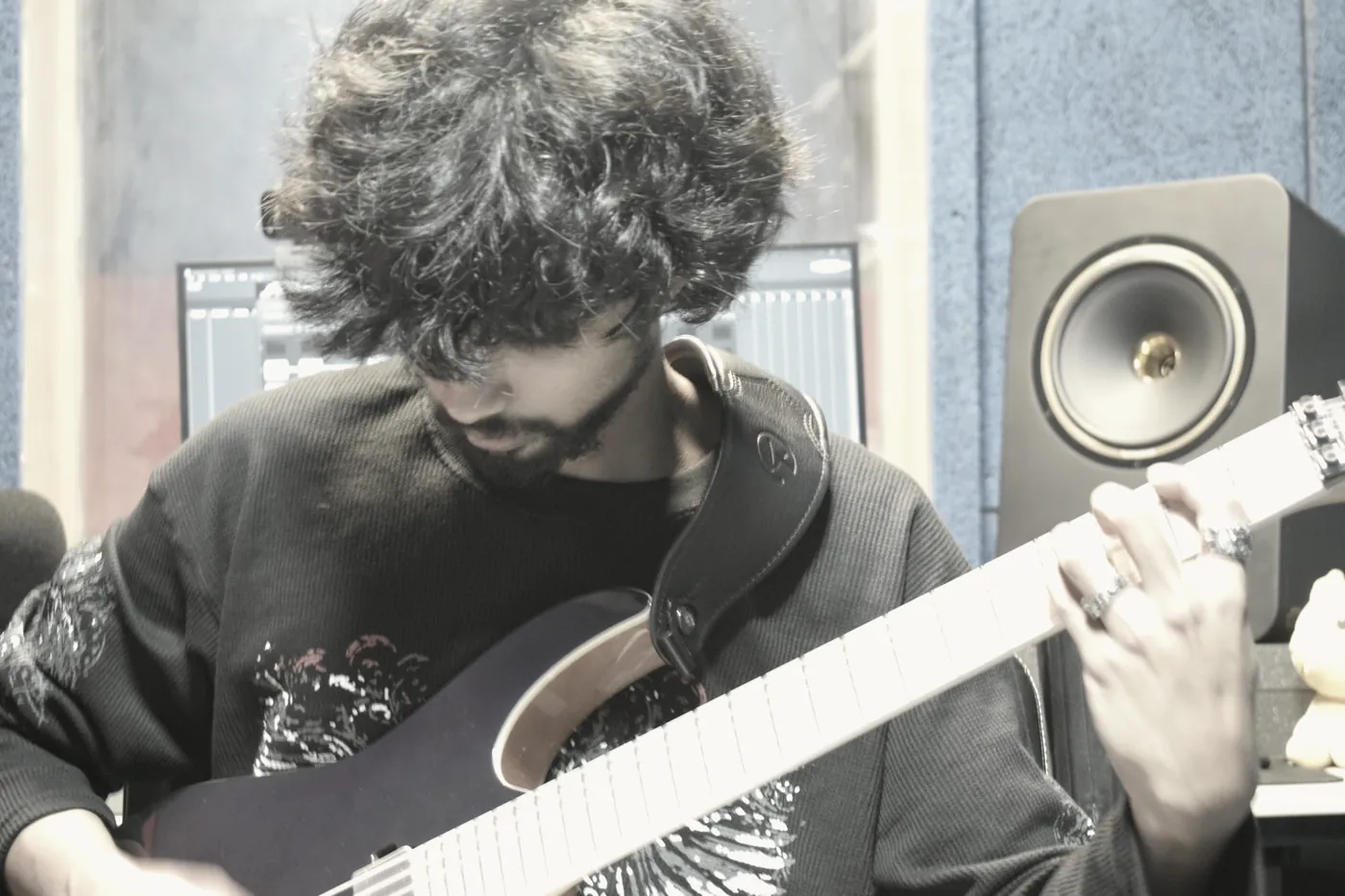 A guitarist mid-take at the desk, framed for use as campaign artwork.